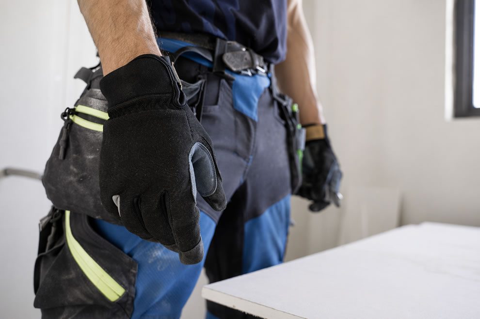 tradesman with work gloves standing by plasterboard